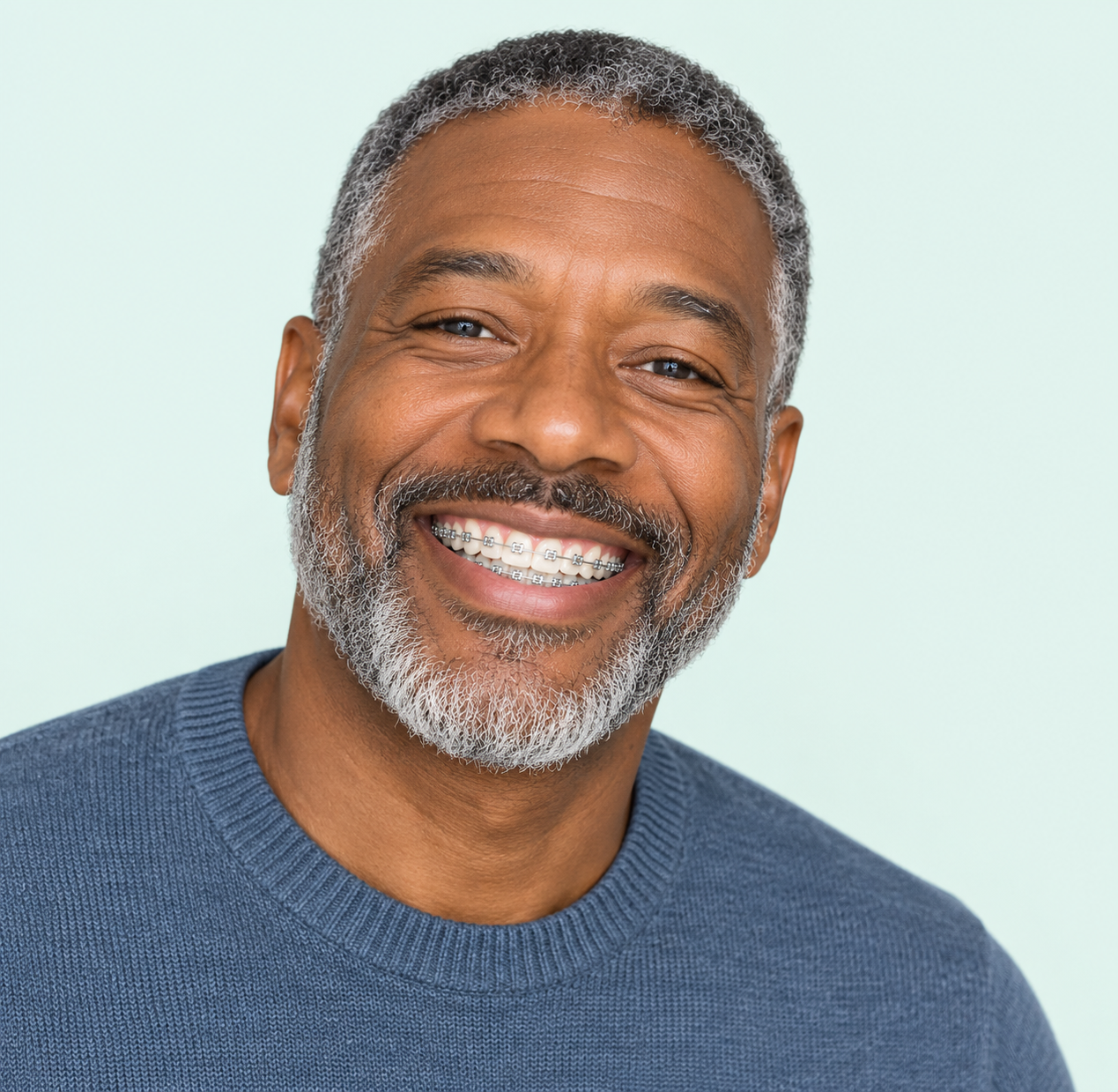 A smiling man with a gray beard wearing braces