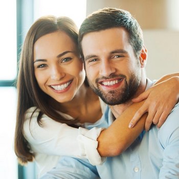 A woman is holding her Invisalign and smiling